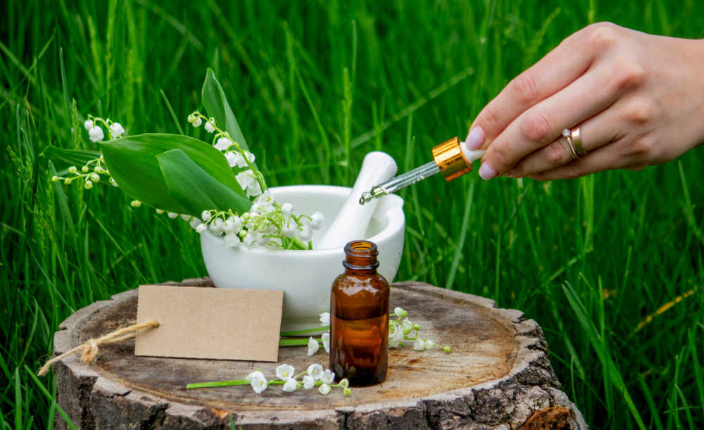 Glass bottle of lily of the valley essential oil with fresh flowers.